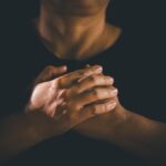 Hands,Clasped,In,Prayer,Over,The,Holy,Bible,,The,Faithful