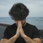 Young,Man,With,Beard,Prays,Outdoors,On,Seaside,Promenade,Showing
