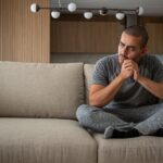 Depressed,Man,,Sitting,In,The,Living,Room,Of,His,House,