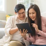 Happy,Excited,,Smiling,Asian,Young,Couple,Love,Using,Tablet,Pc,