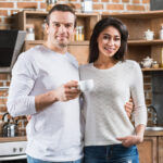 Happy,Multiethnic,Couple,Smiling,At,Camera,While,Standing,Together,In